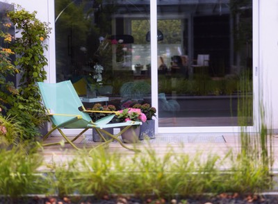 Ein Moderner Garten in München mit  Wasserbecken und Holzdeck und gemütlichem Gartenstuhl. Schöne Gartenmöbel für einen kleinen Garten. Kleiner Garten mit Wasser, Gartenplanung Renate Waas, Gartenarchitektin München